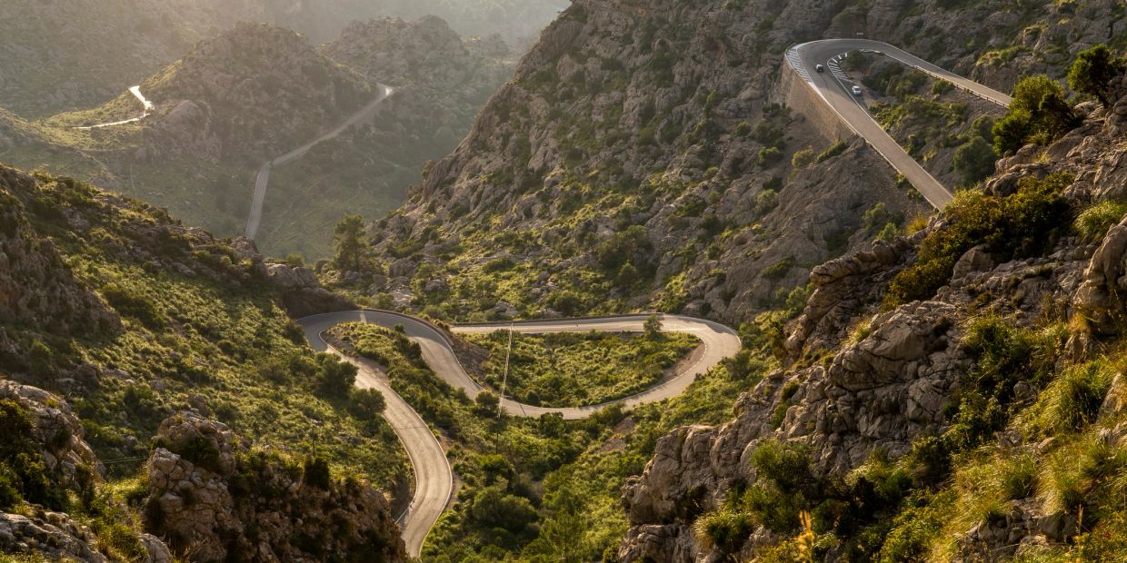 Winding mountain road with rocky terrain and greenery.