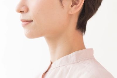 Close-up of a person's lower face and neck with a light pink shirt.