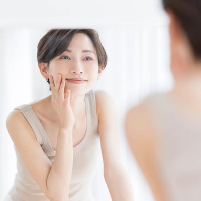A woman with short hair smiling gently while looking in the mirror.