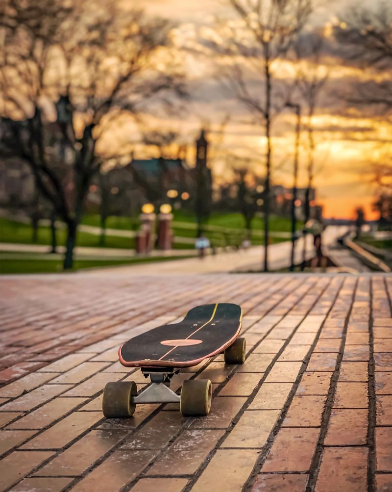 Lone skateboard deck outdoor on paving stone footpath in Syracuse University Campus. Skateboard on paved path in park.