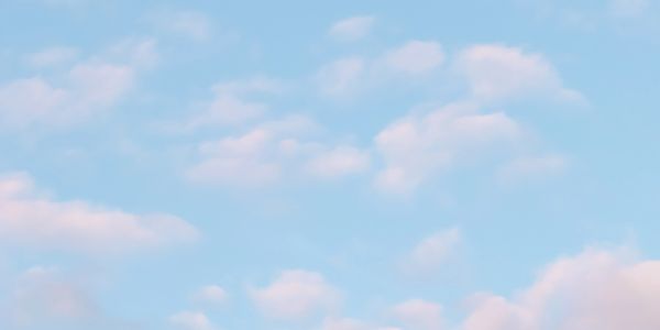 Soft pink clouds scattered across a clear blue sky.