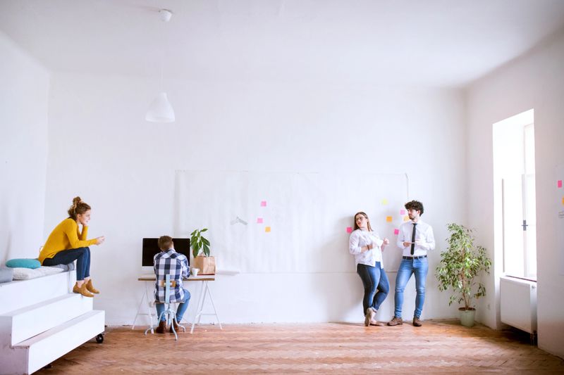 Young group of colleagues working on new project together in a startup company office. Working in co-working space.