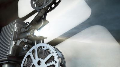 Vintage film projector casting light beams.