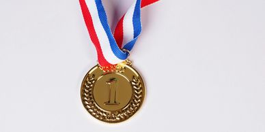 Gold medal with number one and red, white, blue ribbon.