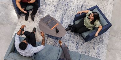 Four people having a discussion in a modern office lounge area.