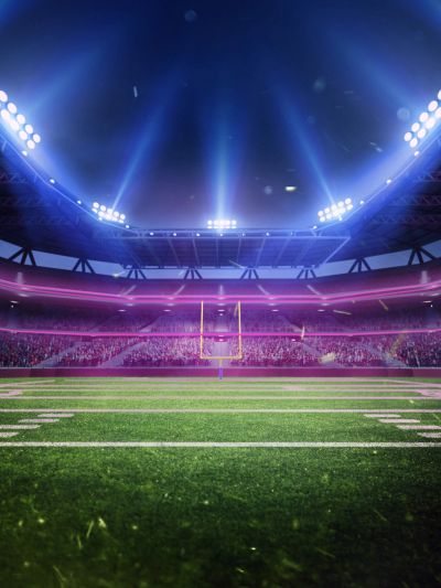 Empty football field with bright stadium lights.