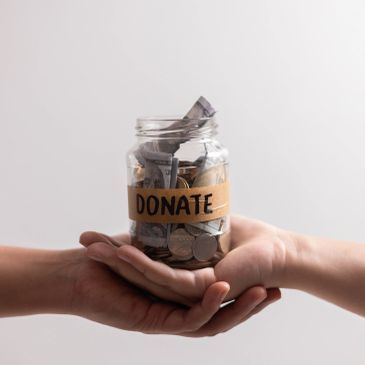 Hands holding a donation jar filled with money.