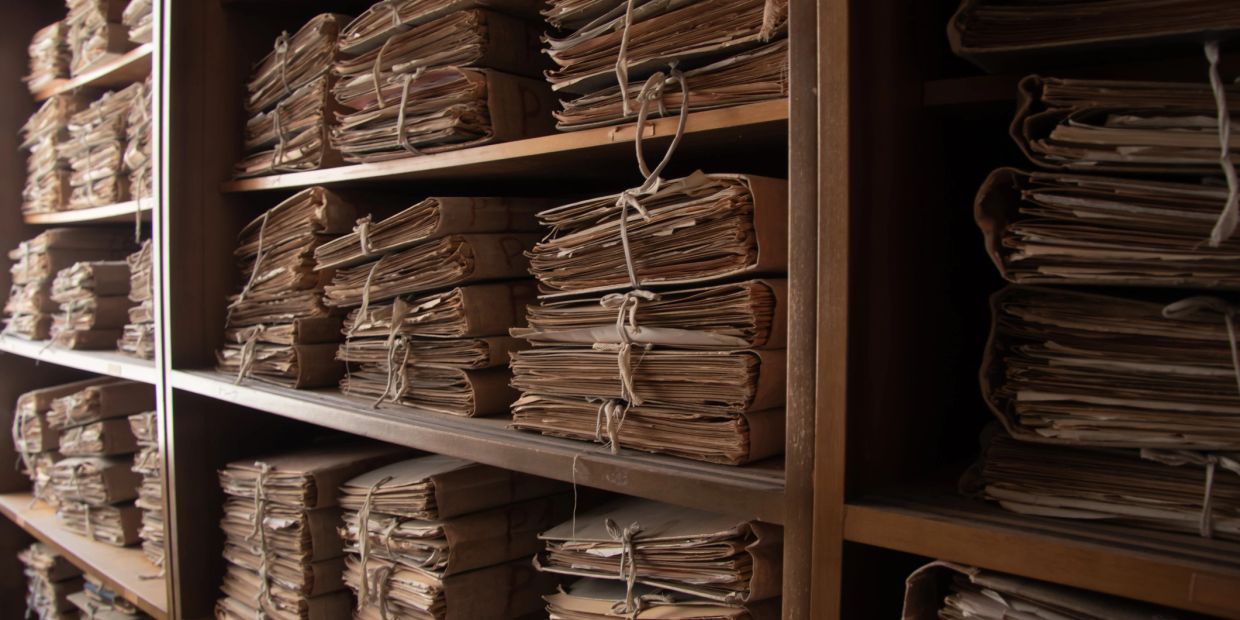 Stacks of old tied documents on shelves.