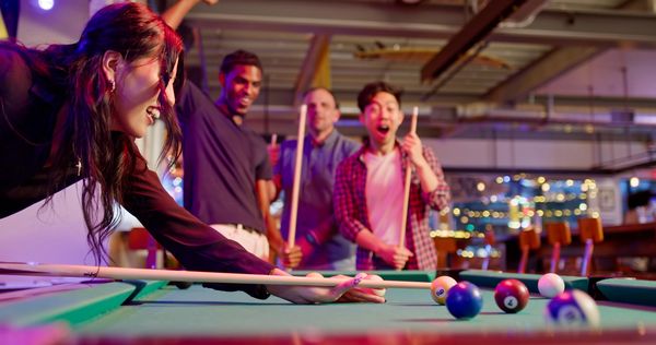 Group of friends playing pool in a lively setting.