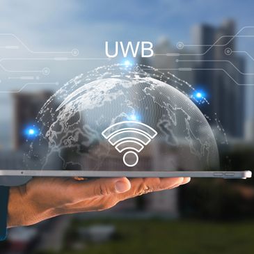 Hand holding tablet with digital globe and UWB wireless signal graphics.