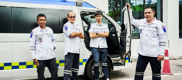 Four paramedics standing confidently by an ambulance, ready to respond to emergencies.