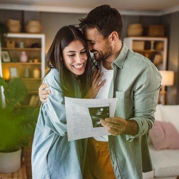 Happy couple joyfully embracing while looking at ultrasound results.