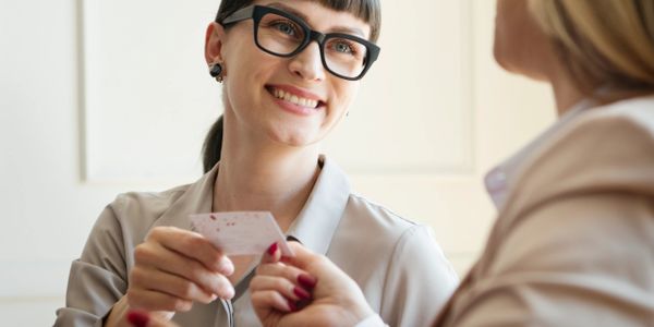 Two women exchanging a business card during a meeting.
