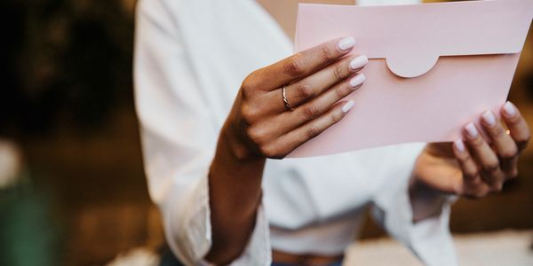Woman holding a pale pink envelope.