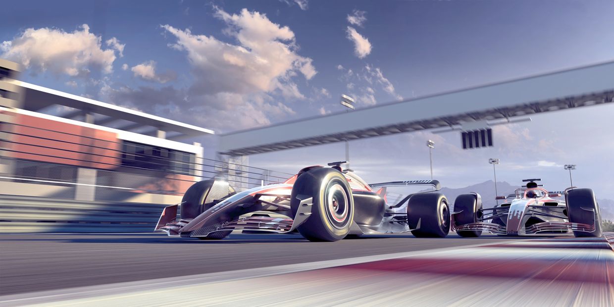 Two Formula 1 cars racing on a modern circuit under a partly cloudy sky.