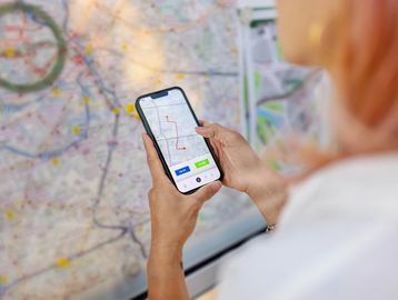 Person holding phone with map app and map background.