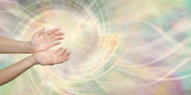 Two open hands reaching towards a glowing, swirling light.