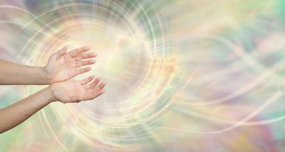 Open hands reaching toward swirling light and colors.