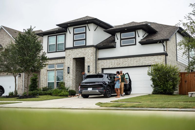 Multiethnic family coming home and putting their electric vehicle to charge. Sustainable energy with solar panels on their rooftop. Joy, carefree, togetherness, and environmental consciousness portrayed in a suburban setting.