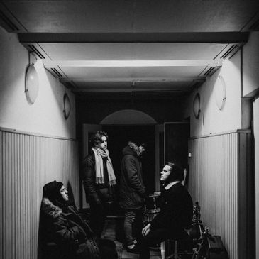 Black and white photo of four people in a narrow hallway.