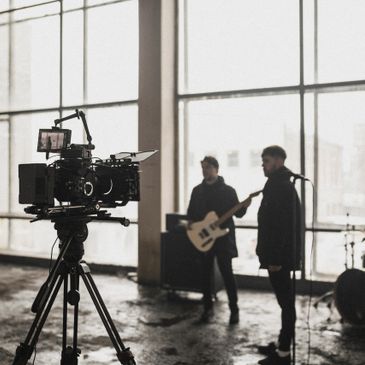 Professional camera filming musicians in an industrial setting.