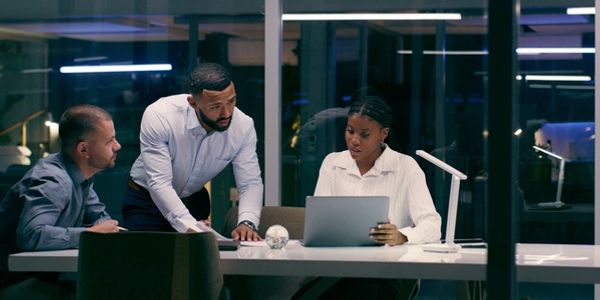 Three colleagues collaborating on a project at night in an office.