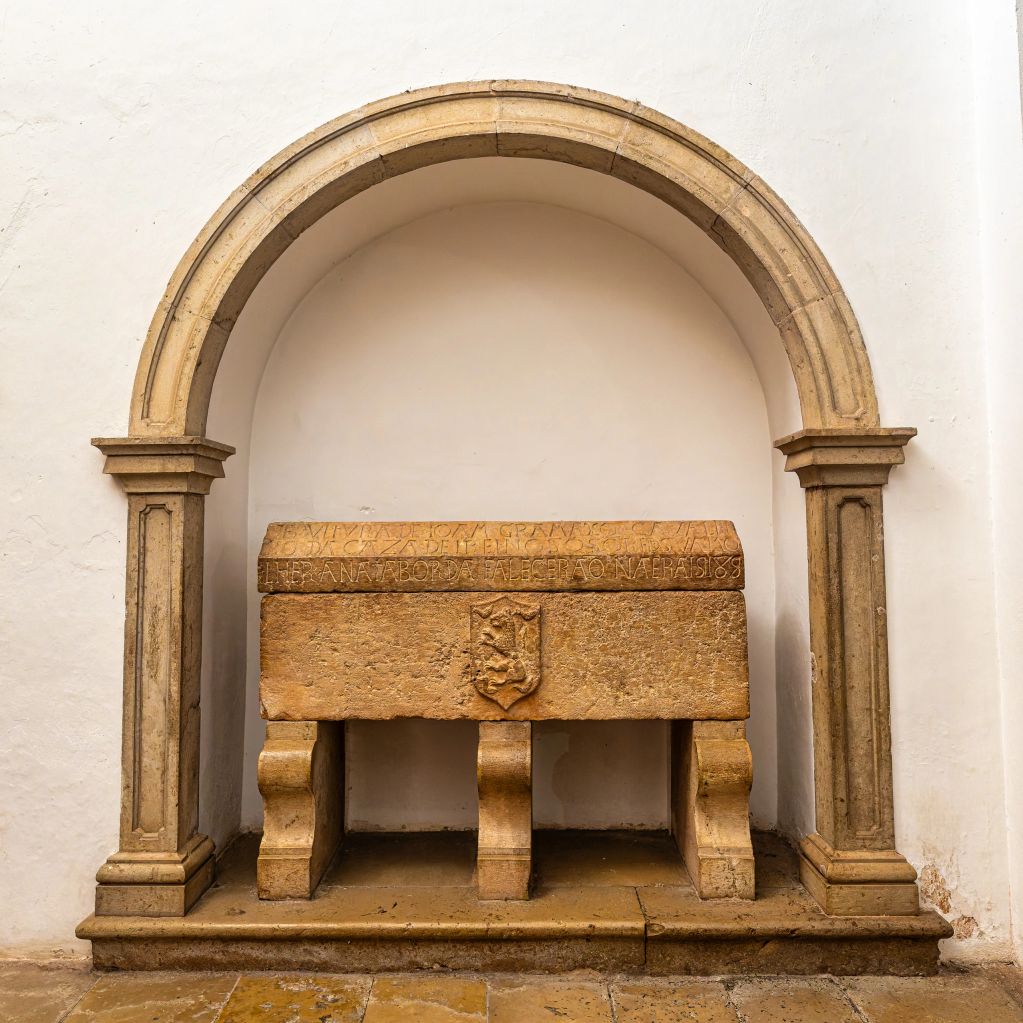 Stone tomb with an inscription, set within an arched alcove.