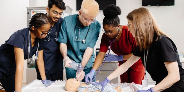Medical team practicing infant CPR on a baby mannequin during training.
