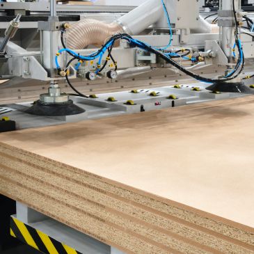 Industrial machine processing layered plywood sheets in a factory setting.