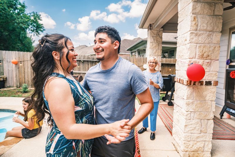 Multi generation Latino family dancing at the backyard party.  All dressed in casual summer clothes. Exterior of backyard of private home in Houston, Texas.