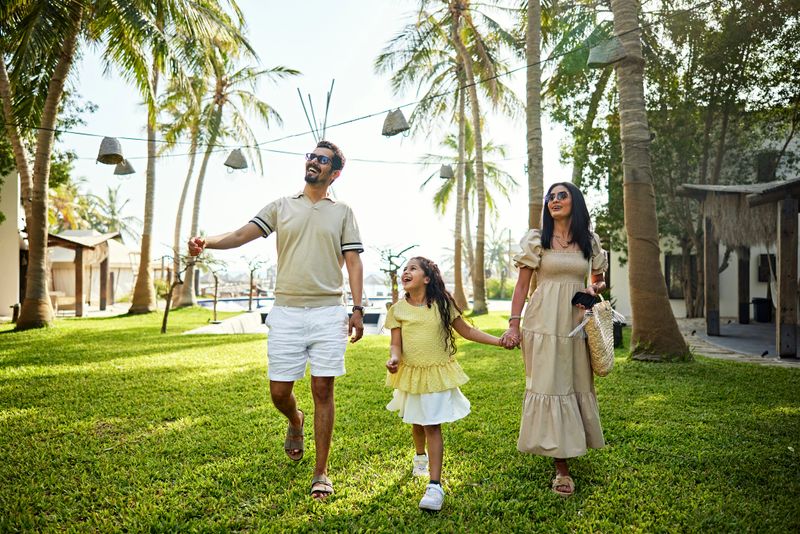 Happy family having fun while walking in resort garden during vacations