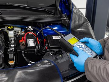 Mechanic using diagnostic tool on car engine.