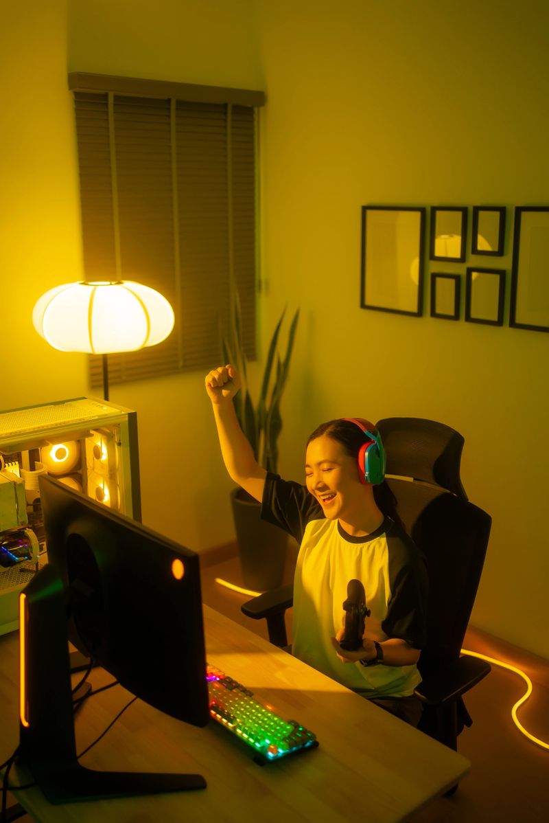 Asian woman using joystick playing computer game feeling happy after winning in game sitting in gaming room at home.