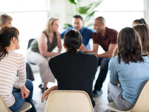 A group of diverse people sitting in a circle engaged in conversation.