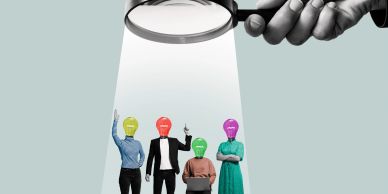 Four people with light bulb heads under a magnifying glass spotlight.