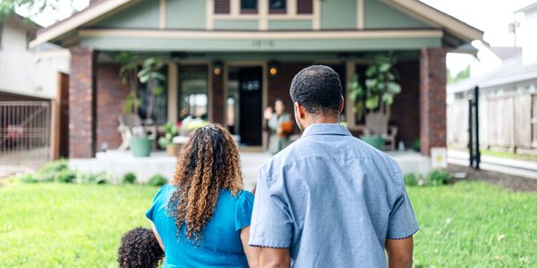 Family standing outside a house, greeting someone at the door.