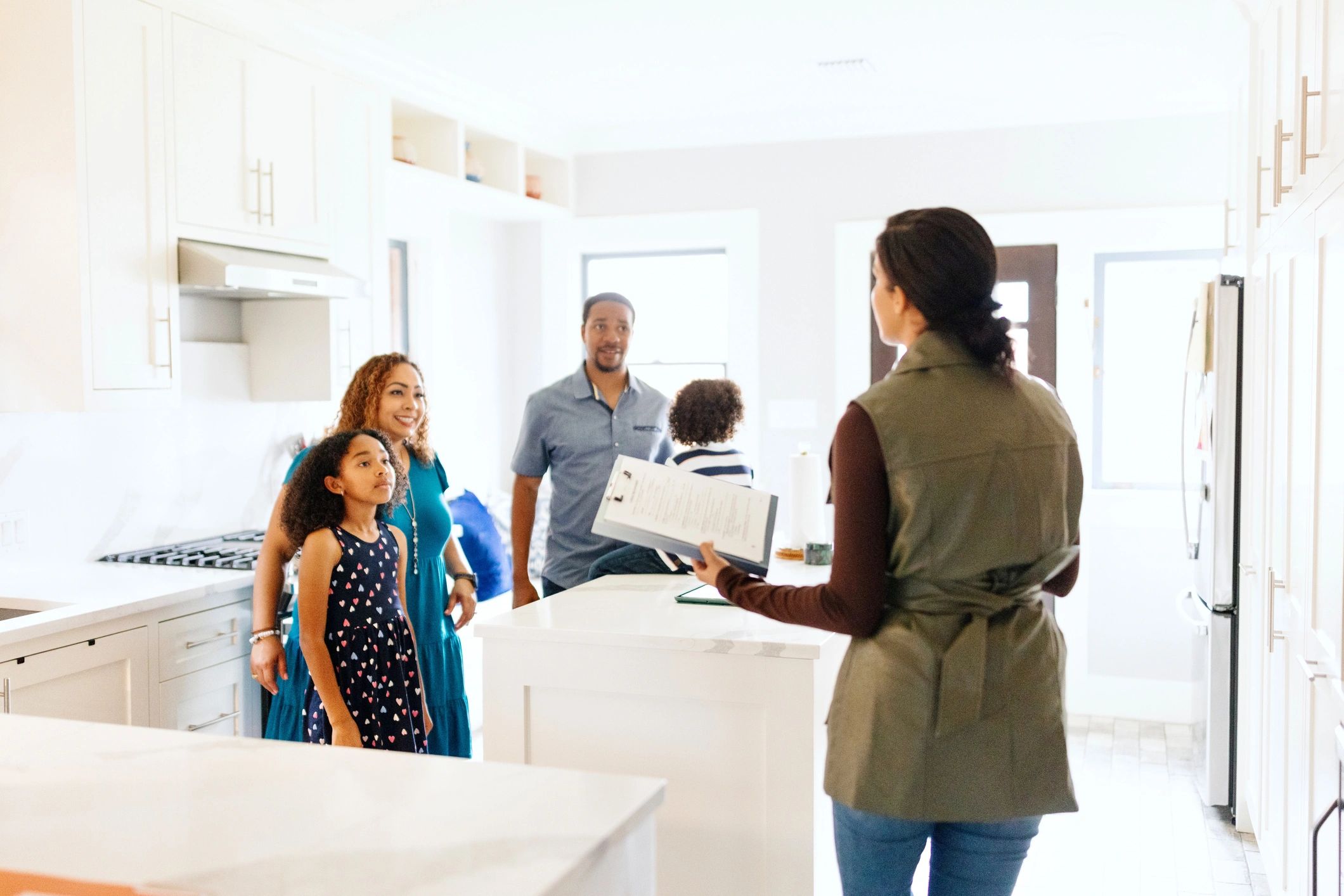 Real estate agent showing a family a modern kitchen during a home tour.
