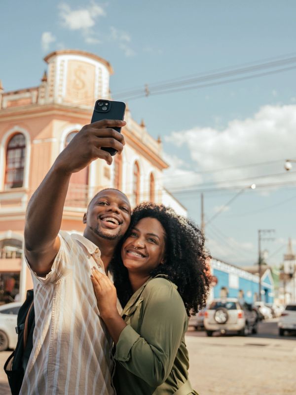 Couple happily takes a selfie in a sunny, historic town square.
