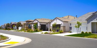 A sunny suburban street with modern houses and clear blue sky.