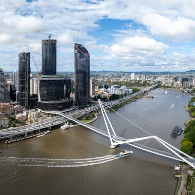 Modern bridge and skyscrapers along a river in a cityscape under a partly cloudy sky.