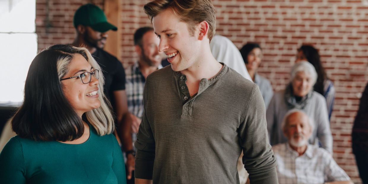 Two people smiling and chatting in a social setting.