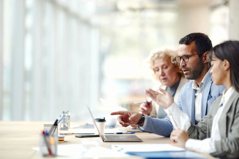 Team of entrepreneurs cooperating while reading an e-mail on a computer in the office. Copy space. Focus is on man.
