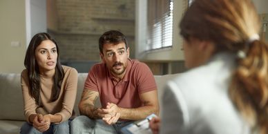 A couple attentively talking to a therapist in a counseling session.