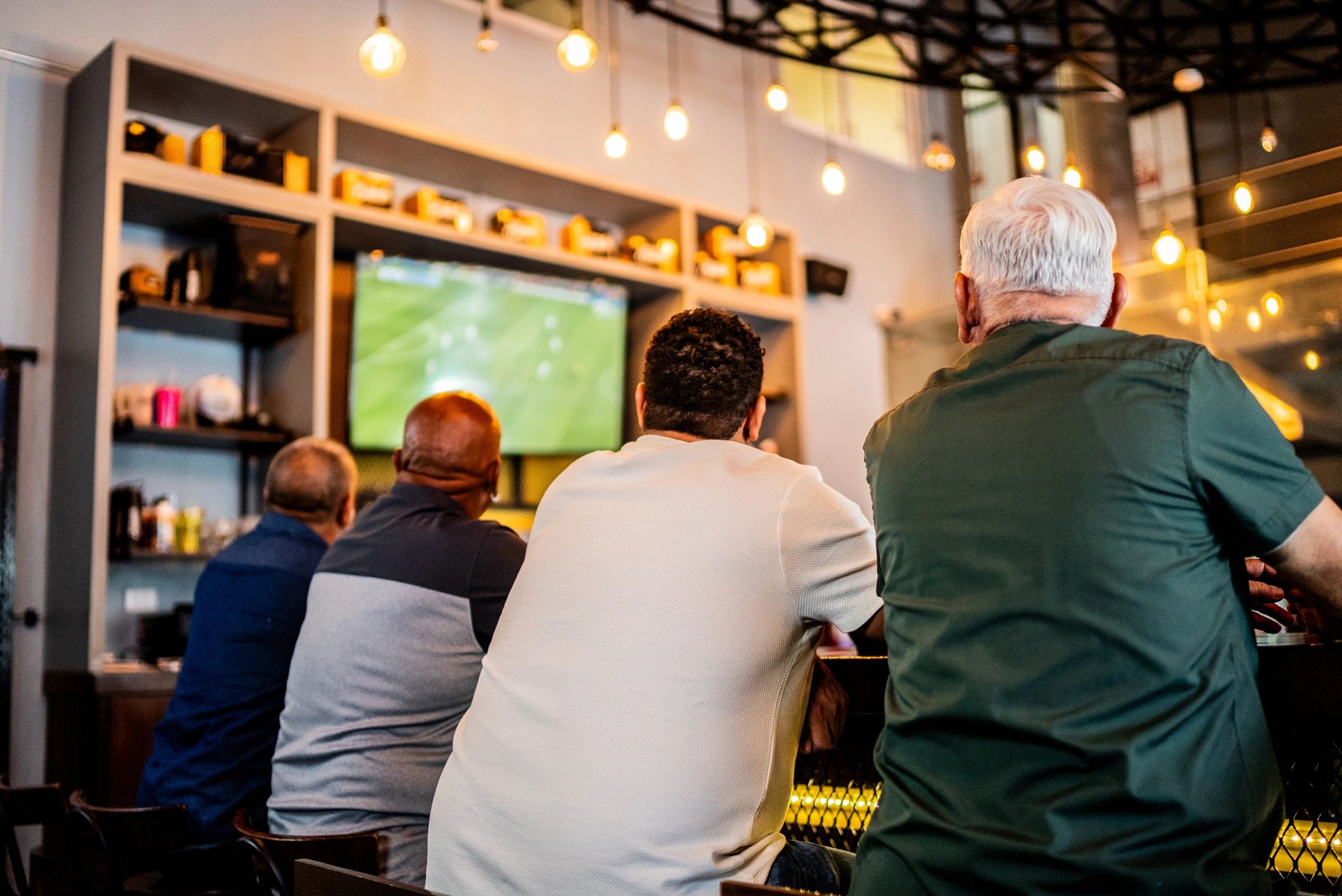 Senior men watching soccer match on the bar