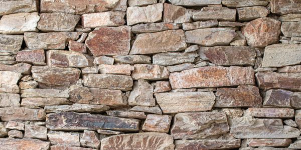Rustic stone wall with uneven, natural rocks tightly stacked.