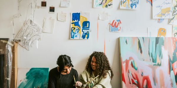 Two women painting together in an art studio.