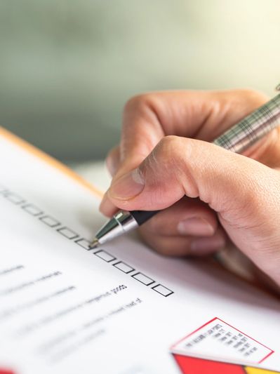  a white woman holding a pen and completing a checklist on an a4 page