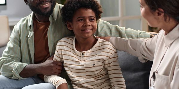 A father and son smiling during a conversation with a female therapist.