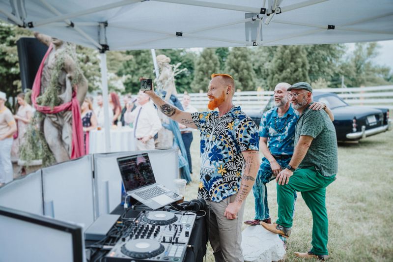 A wedding DJ takes a break from mixing to use a smart phone to film the wedding ceremony.