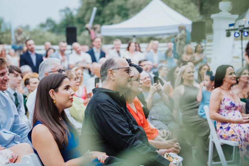 Supportive and loving friends and family attend outdoor wedding ceremony for gay couple.